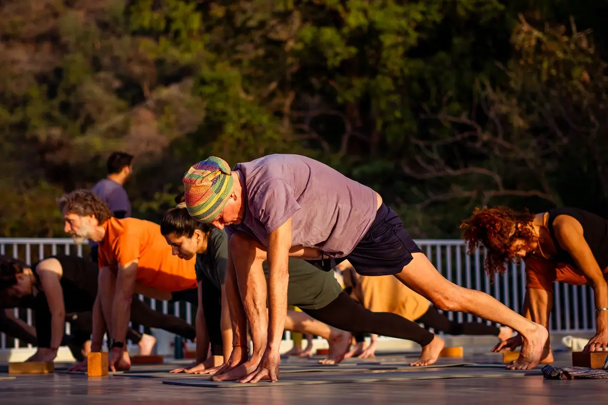 Students practising Warrior pose outdoors during a yoga teacher training in Rishikesh